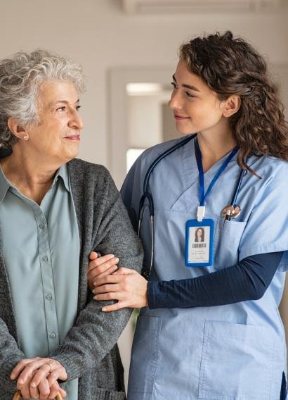 Young caregiver helping senior woman walking. Nurse assisting her old woman patient at nursing home. Senior woman with walking stick being helped by nurse at home.